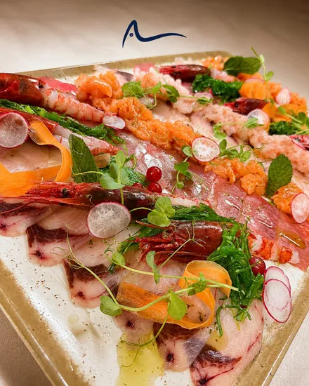 A raw seafood platter with prawns, sliced fish, radish and samphire