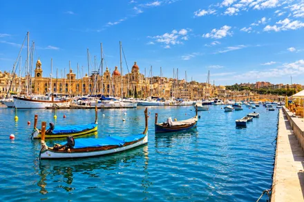 Traditional Maltese luzzu boats moored in the Grand Harbour, the Three Cities behind them