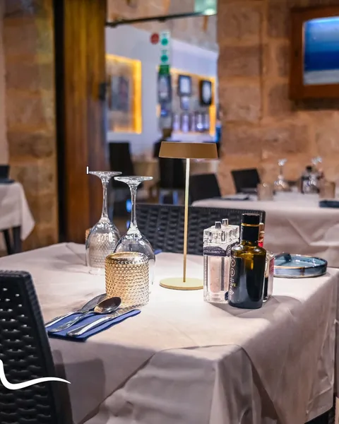A small dining room set for service, white linen and low lamps