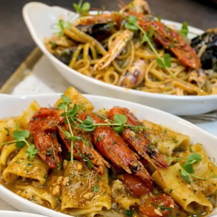 Two bowls of pasta with whole prawns and mussels