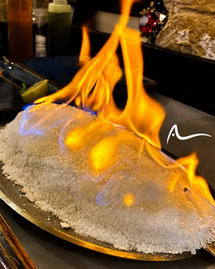 A whole fish baked in a salt crust, flamed at the table