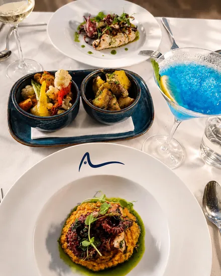 A table mid-service with grilled squid, octopus, vegetables and glasses