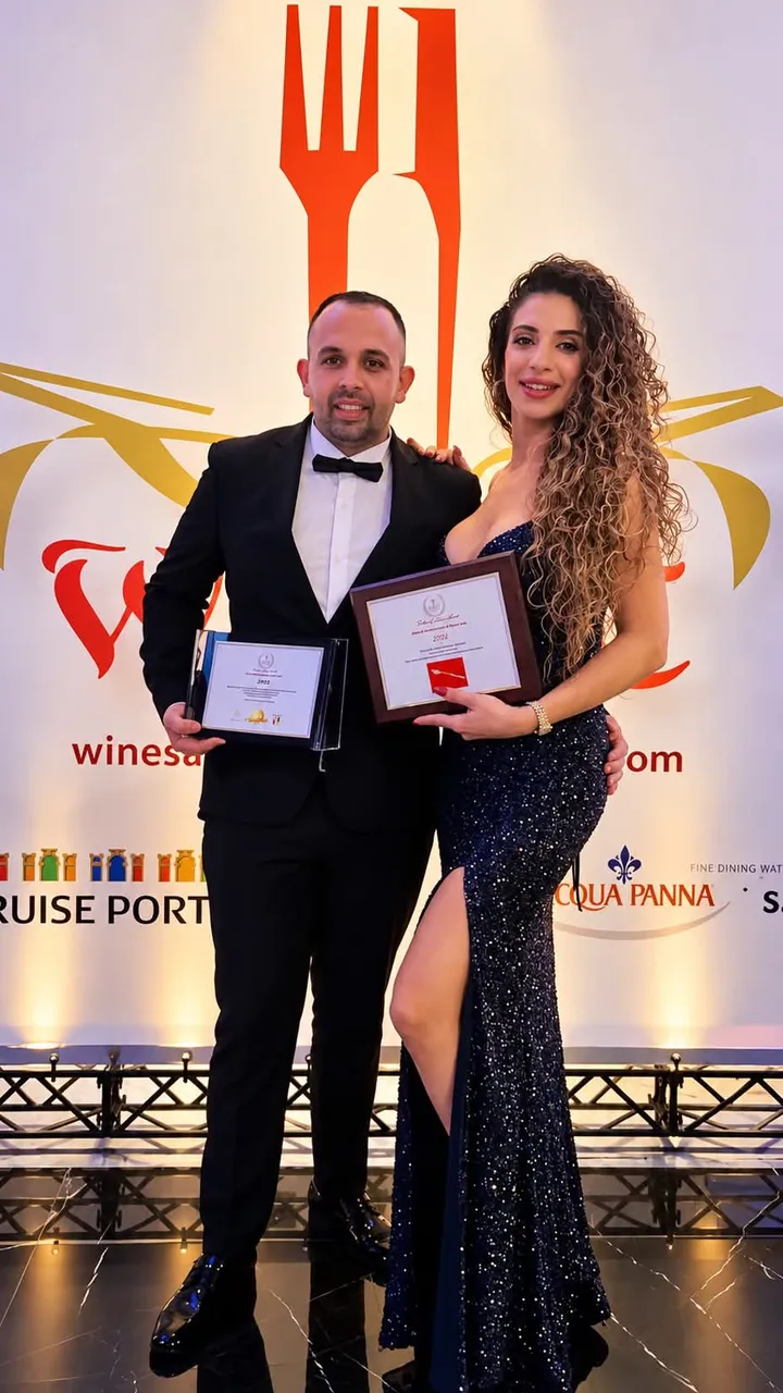 Matteo Cardona and Brenda Bartolo in evening dress, holding framed certificates at a restaurant awards evening