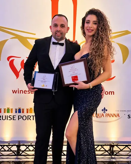 Matteo Cardona and Brenda Bartolo in evening dress, holding framed certificates at a restaurant awards evening