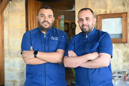 Two chefs in blue Acqua Blu jackets standing arms folded in the doorway of the dining room